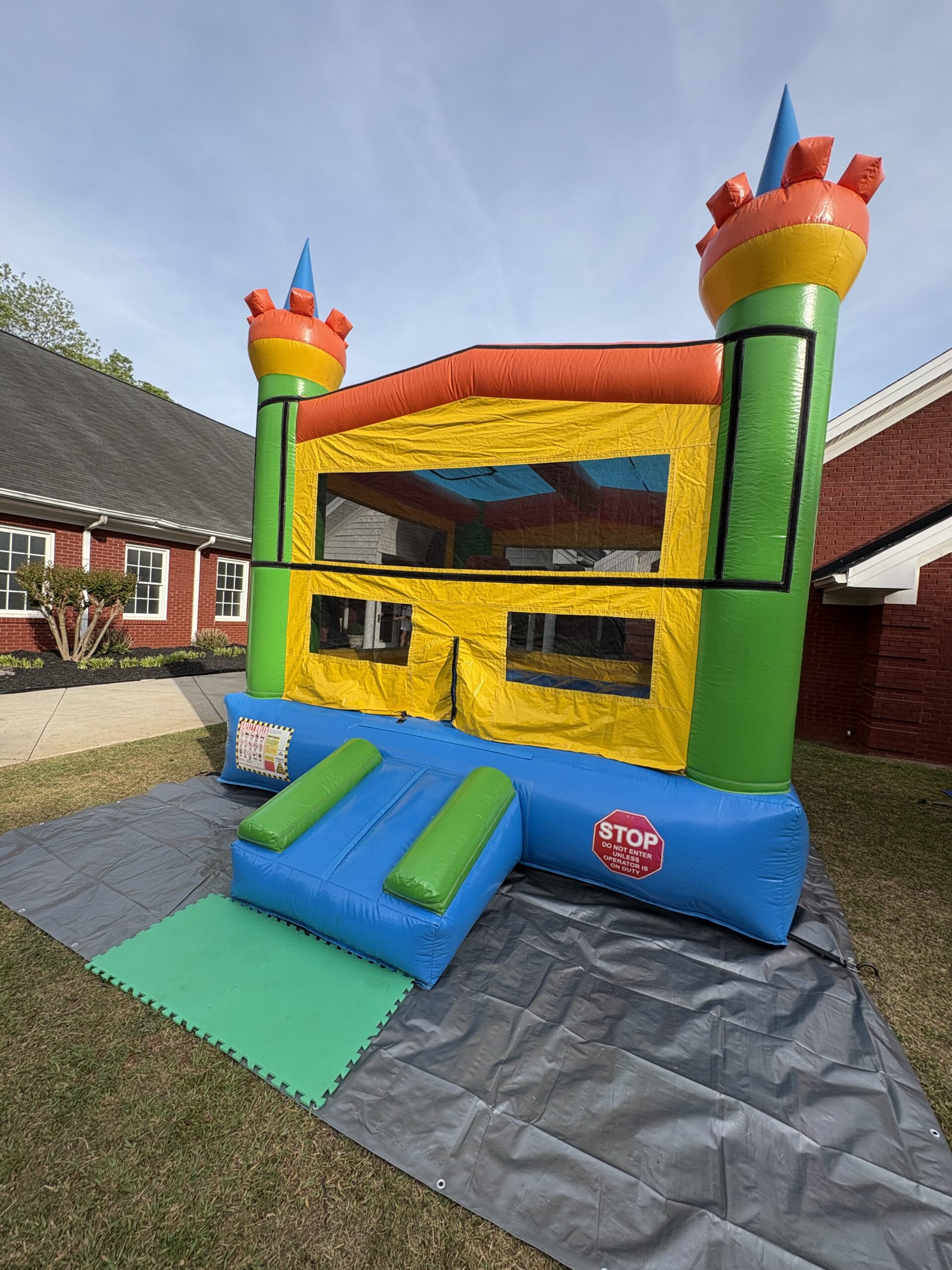 Yellow and green bounce house with basketball hoop